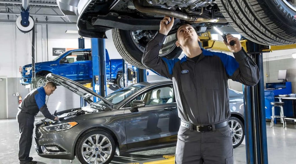 Ford service technician under a lift working on a vehicle
